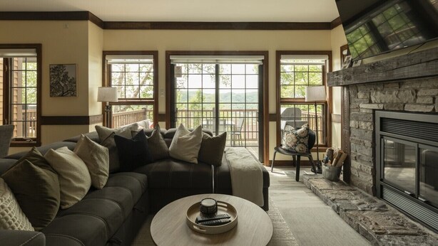 Una sala de estar con un sofá modular, una chimenea y ventanas amplias.