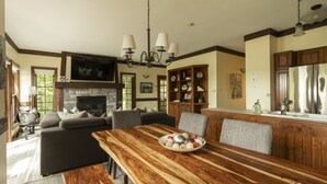 Un salón amplio con chimenea, un comedor con mesa de madera y una cocina con armarios de madera.