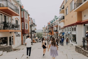 A pedestrian street lined with multi-story buildings, some with balconies and shops on the ground floor.