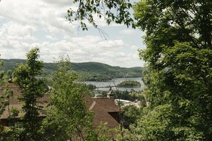 A view of a lake surrounded by hills and trees, with buildings in the foreground.