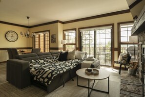 A spacious living room with a large sectional sofa, a round coffee table, and a fireplace.