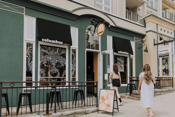 A building with a green facade, two windows with the name 'Columbus Cafe & Co' and a sign above the door.