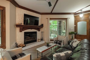 A living room with a fireplace, a television, a sofa, and a dining table.