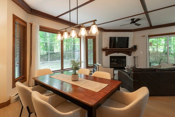 A dining area with a wooden table and chairs, a fireplace, and a television.