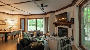 A living room with a fireplace, a dining area, and large windows. - Just steps from Tremblant • Free shuttle (Mont-Tremblant)