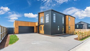Un bâtiment moderne à deux étages, doté d’un garage, d’un revêtement en bois et d’une allée en béton.