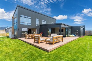 A modern two-story house with a patio area featuring outdoor furniture. - Wharewaka Escape (Taupo)