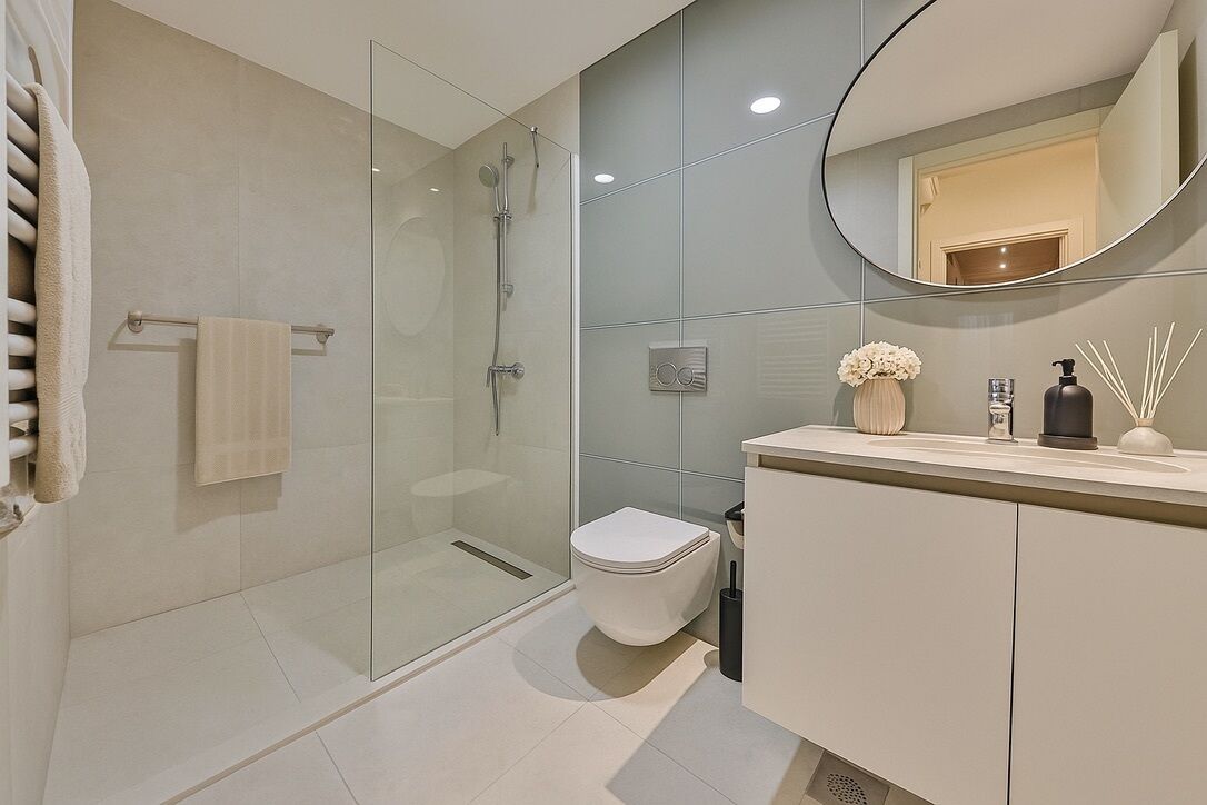 A modern bathroom with a glass shower enclosure, a toilet, and a vanity with a mirror.
