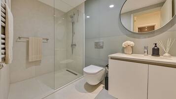 A modern bathroom with a glass shower enclosure, a toilet, and a vanity with a mirror.