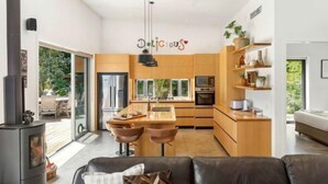 Una cocina moderna con armarios de madera, una isla central con taburetes y un horno empotrado, junto a un amplio ventanal.