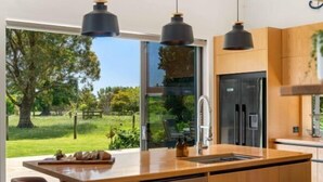 Una cocina moderna con una isla grande, electrodomésticos integrados y vistas a un jardín exuberante.