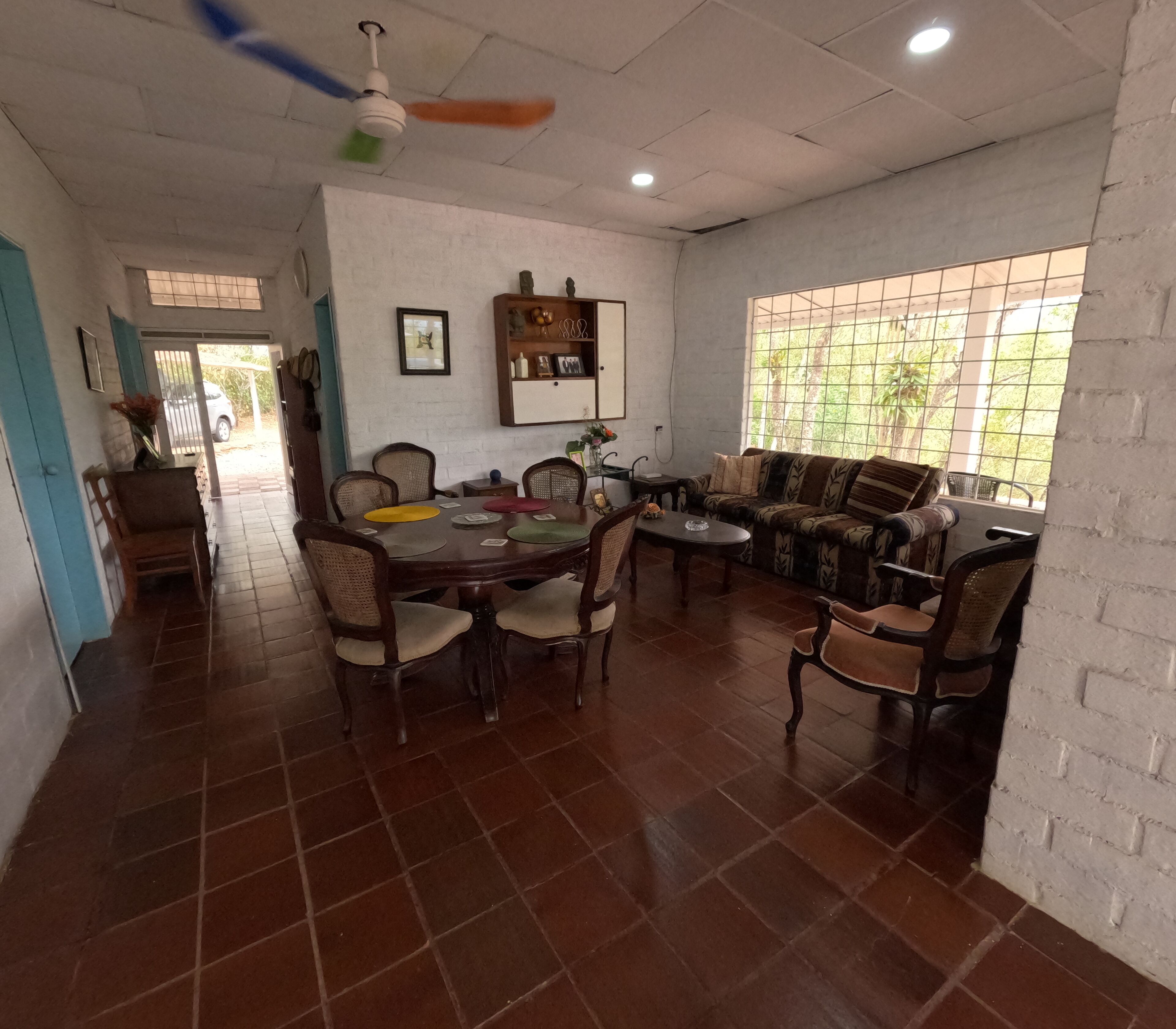 Una habitación amplia con una mesa de comedor, sillas, un sofá y un ventilador de techo.
