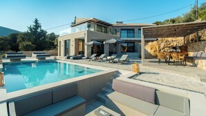 Uma casa moderna com piscina, área de estar externa e uma parede de pedra.
