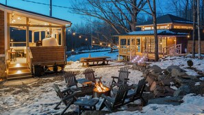 A cozy outdoor seating area with a fire pit, wooden chairs, and a picnic table.