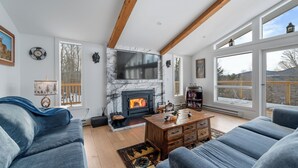 A spacious living room with a fireplace, large windows, and a cozy seating area.