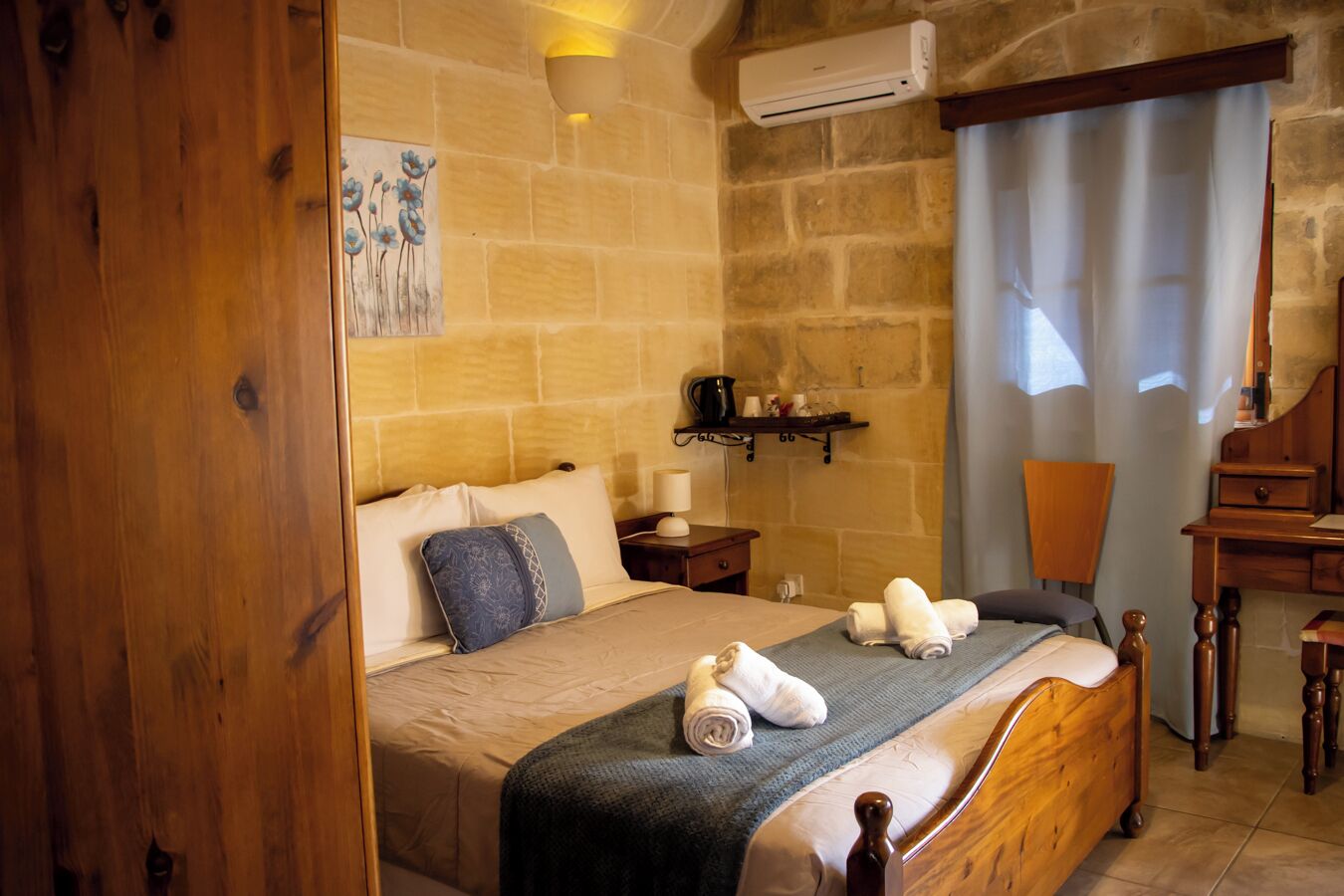 A bedroom with a wooden bed, a nightstand, a desk, and a chair.