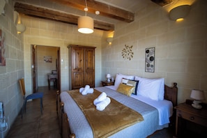 A bedroom with a large bed, wooden wardrobe, and a chair. - il figolla (Xaghra)