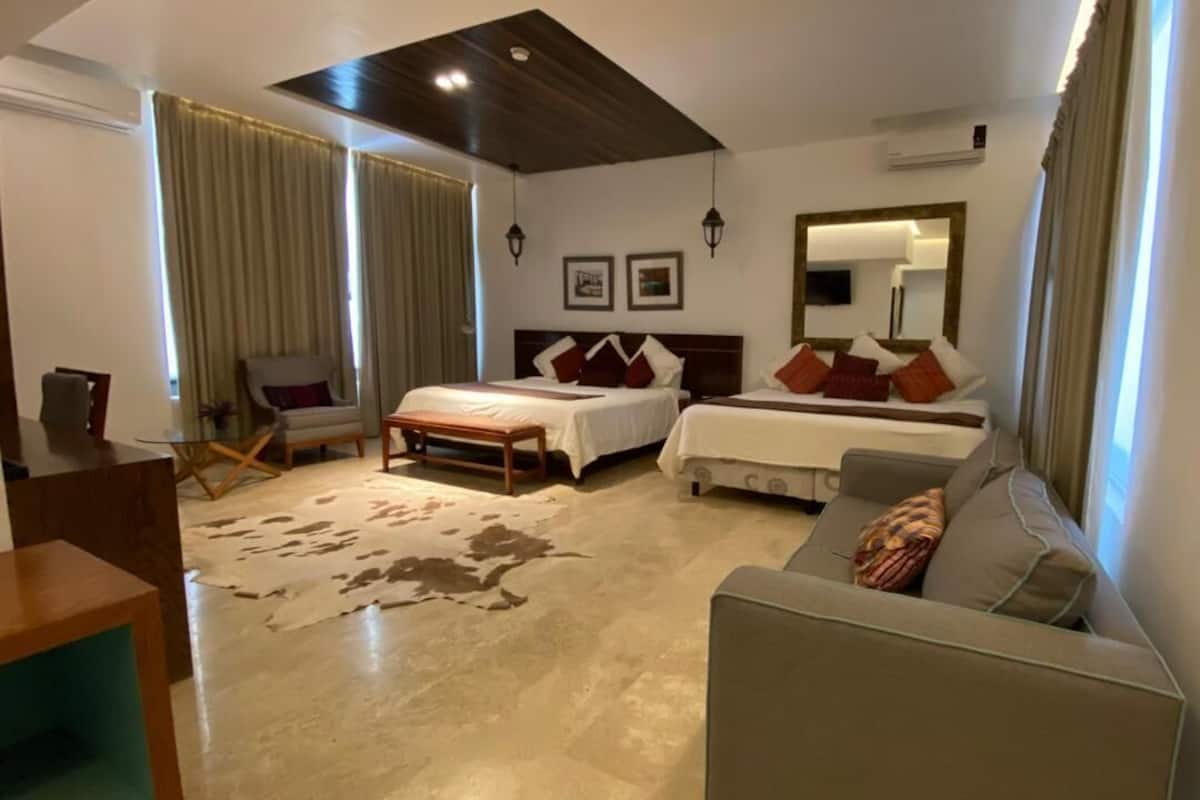 Una habitación de hotel moderna con dos camas, un sofá, una mesita y un espejo grande.
