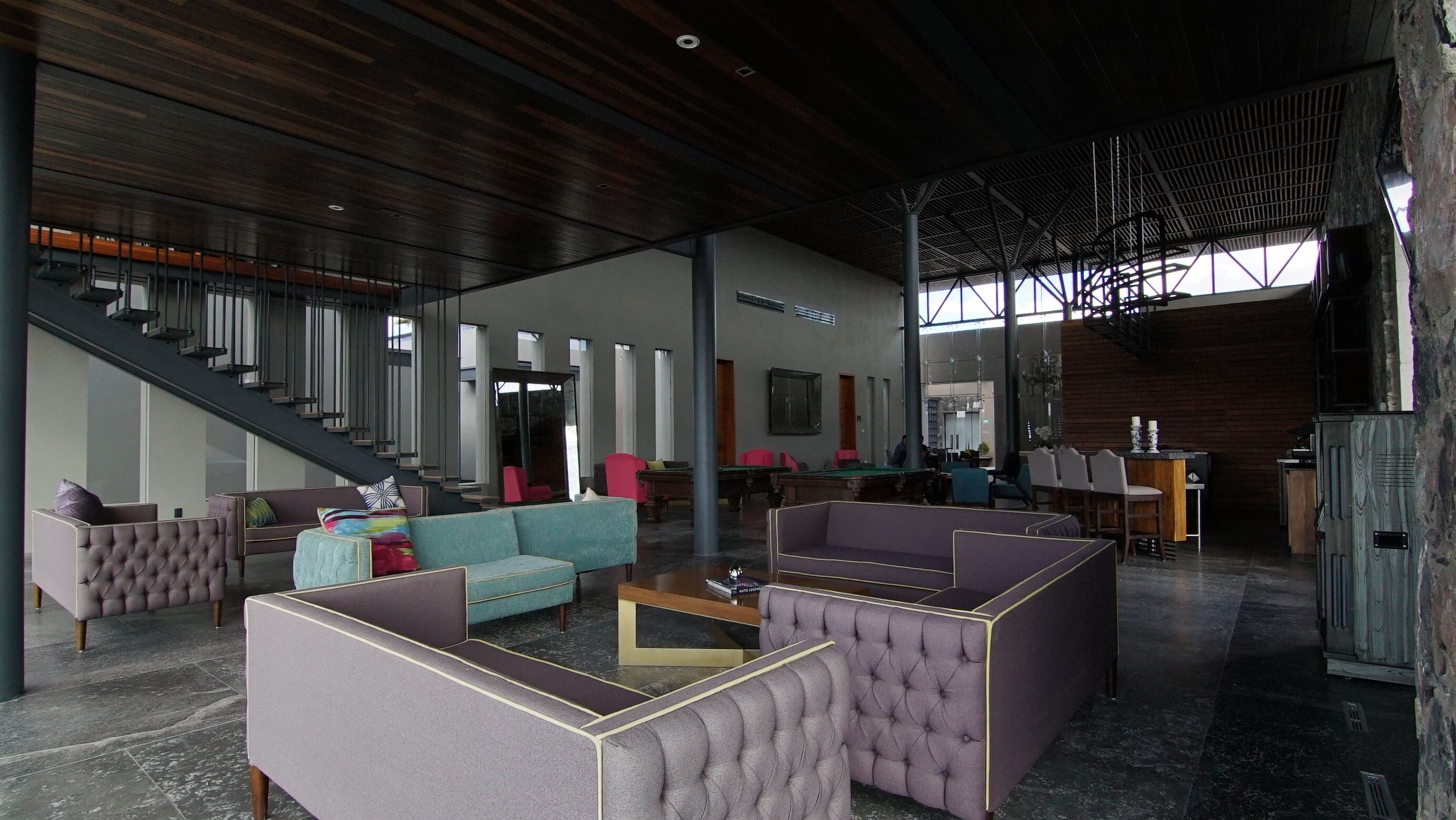 Eine geräumige Lobby mit hoher Decke, modernen Möbeln und einer Treppe zu den oberen Etagen.