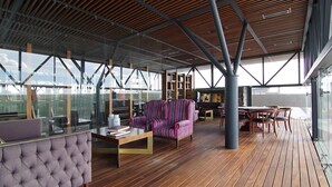 A modern lounge area with a wooden floor, striped armchairs, a tufted sofa, and a glass partition. - Rancho Canto de Sal Luxury Hotel & SPA (Salinas de Hidalgo)