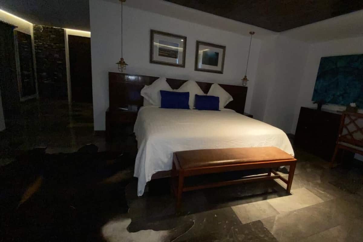 Un dormitorio con una cama grande, un banco de madera, una mesita de noche y un escritorio con una silla.