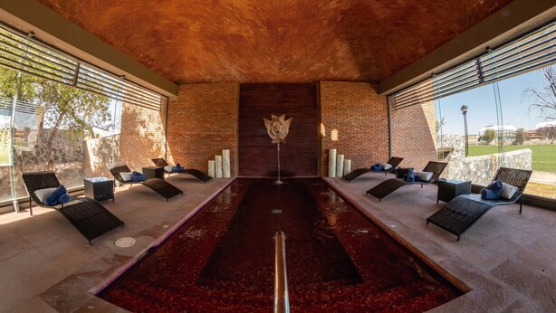 A sunlit indoor pool area with lounge chairs and a central water feature. - Rancho Canto de Sal Luxury Hotel & SPA (Salinas de Hidalgo)