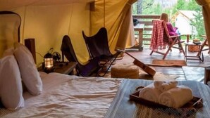 A tent with a bed, chairs, a lantern, and a view of the outdoors. - Rancho Canto de Sal Luxury Hotel & SPA (Salinas de Hidalgo)
