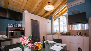 Una cucina moderna con elettrodomestici in acciaio inossidabile, una zona pranzo con tavolo in vetro e vista sull'esterno.