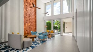 A modern lobby with a curved grey sofa, blue armchairs, and a patterned rug. - Laguna Lakeside, One Bedroom 1603 B5 Premium (Choeng Thale)