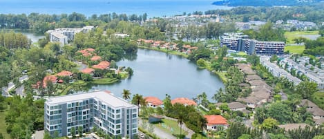 Un complexe hôtelier doté d’un lac central, entouré d’une végétation luxuriante et de bâtiments résidentiels.