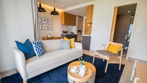 A modern living room with a sofa, a round coffee table, and a dining area with a chair.