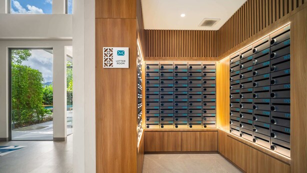 A modern hotel lobby with a wooden wall and a large letter room sign.