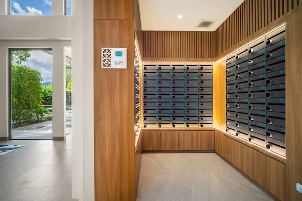 A modern hotel lobby with a wooden wall and a large letter room sign.