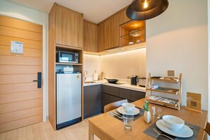 A compact kitchen with wooden cabinets, a built-in microwave, and a dining area with a table set for two.
