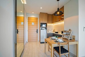 Eine kompakte Küche mit Holzausstattung, einer Mikrowelle, einem Kühlschrank und einem Essbereich mit Tisch und Stühlen.