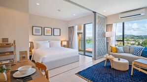 A modern hotel room with a large bed, a sofa, a dining area, and a balcony with a city view. - Laguna Lakeside, One Bedroom 1419 B3 Deluxe (Choeng Thale)