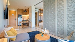 A modern living room with a sofa, a coffee table, and a TV mounted on the wall. - Laguna Lakeside, One Bedroom 1419 B3 Deluxe (Choeng Thale)