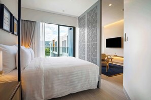 Een hotelkamer met een groot bed, een aan de muur bevestigde televisie en een balkon met uitzicht op de stad.