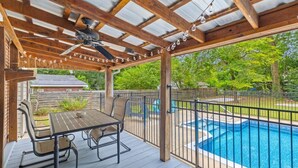 A covered outdoor area with a pool, a table with chairs, and a ceiling fan. - 3BR Pool Home | Free Parking | Near Airport + DT (North Charleston)