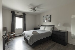 A bedroom with a bed, bedside tables, a chair, a ceiling fan, a window with curtains, and a wall-mounted artwork. - DOWNTOWN | FREE shuttle to Ski Resort • Ice Rink (Mont-Tremblant)