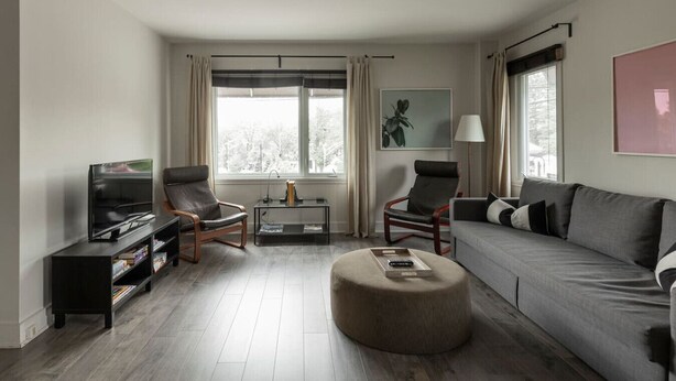 A modern living room with a sofa, two armchairs, a coffee table, a TV, and a bookshelf. - Downtown | FREE shuttle to Ski Resort • Ice Rink (Mont-Tremblant)