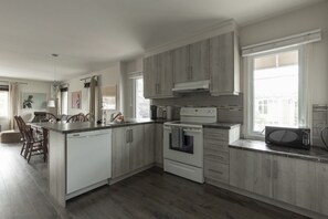 A modern kitchen with a central island, built-in appliances, and a large window providing natural light. - DOWNTOWN | FREE shuttle to Ski Resort • Ice Rink (Mont-Tremblant)