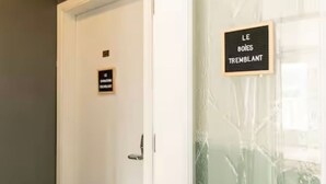 A door with a sign that reads "LE BOIS TREMBLANT" and another sign below it that says "LE MONTAGE DE L'ALBUM". - Downtown | FREE shuttle to Ski Resort • Ice Rink (Mont-Tremblant)