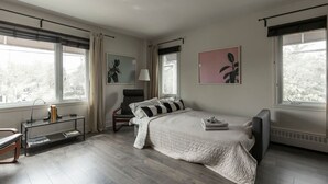 A bedroom with a large bed, a chair, a desk, and two windows. - Downtown | FREE shuttle to Ski Resort • Ice Rink (Mont-Tremblant)