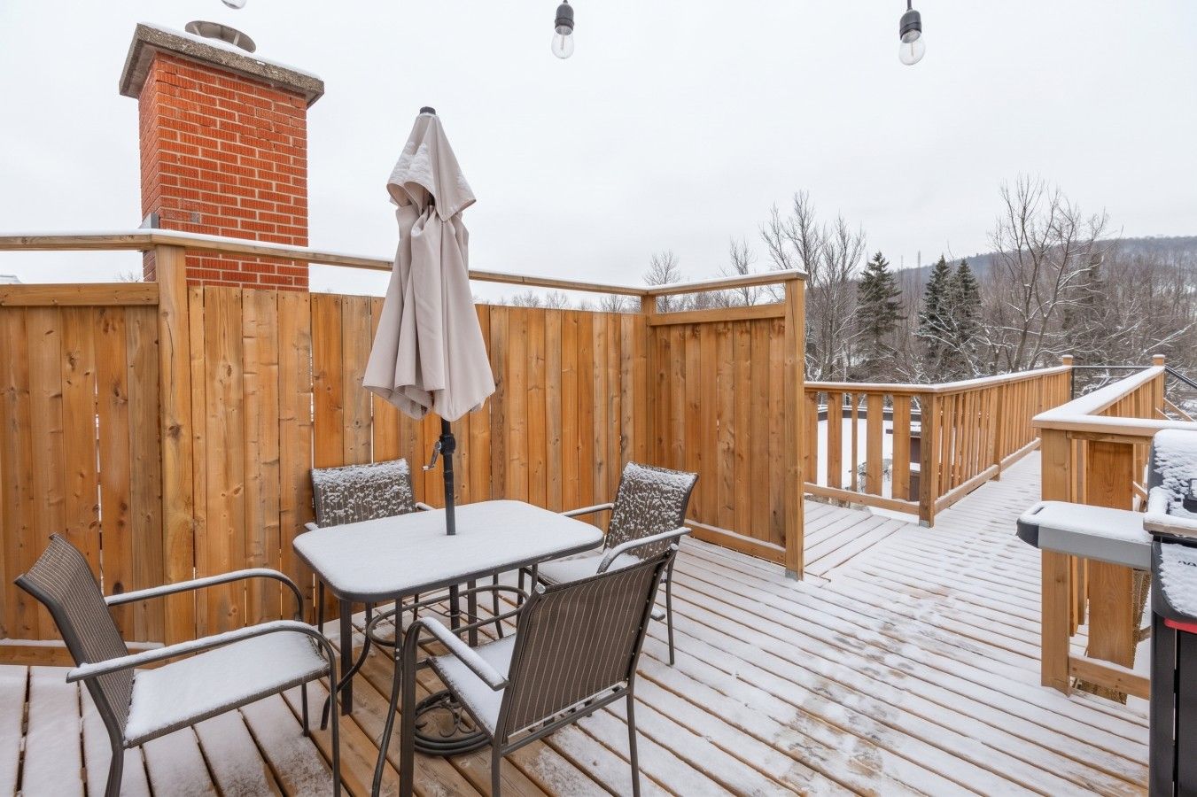 Une terrasse en bois avec une table et des chaises, une cheminée en briques et une clôture en bois.