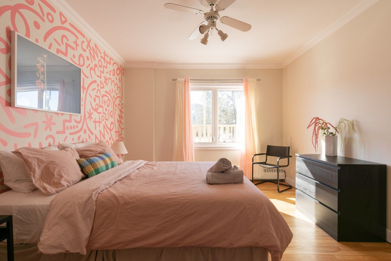 Une chambre à coucher avec un lit, une commode, une chaise et un ventilateur de plafond.