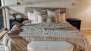 Un dormitorio con una cama grande, una mesita de noche, una lámpara y una planta en maceta.