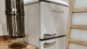 Un refrigerador Galanz blanco con una encimera de madera y un dispensador de agua de acero inoxidable.