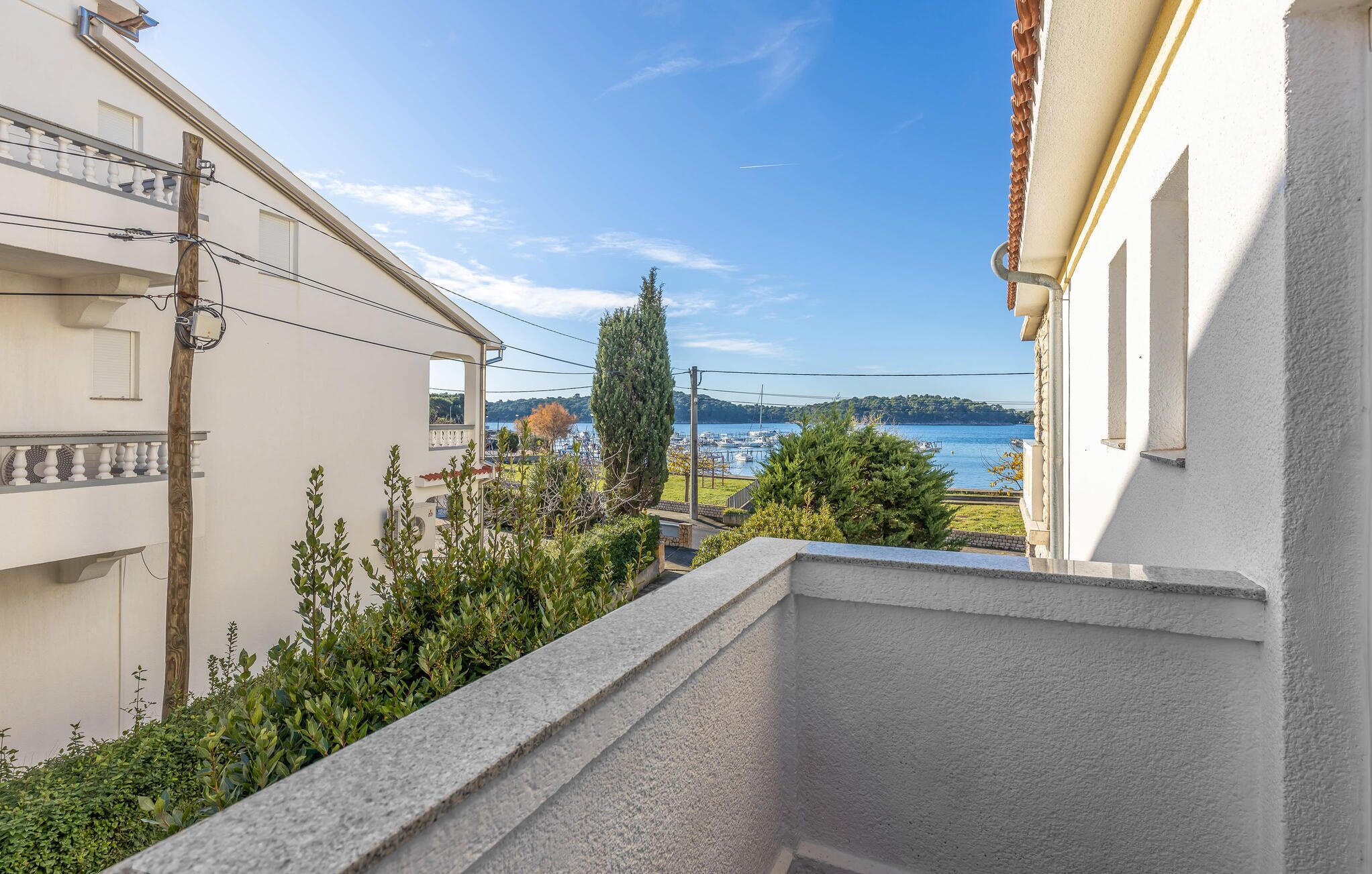 Un balcon avec vue sur une marina et sur des collines à l’horizon.