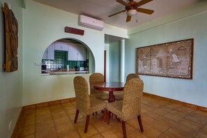 Enjoy meals in this cozy dining area with a round table and four chairs, surrounded by a kitchen with white cabinets and a green backsplash.